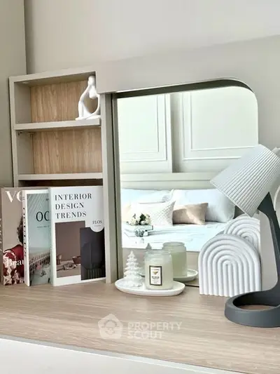 Stylish bedroom decor with modern lamp and design books on wooden dresser.