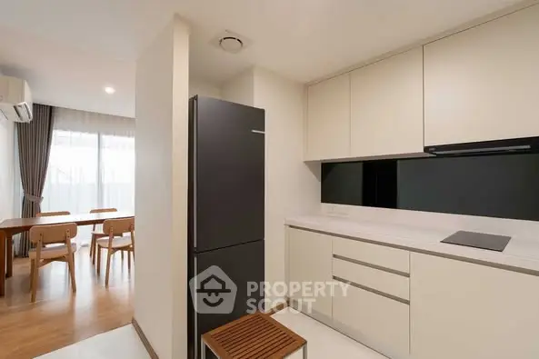 Modern kitchen with sleek cabinetry and dining area in open layout apartment.