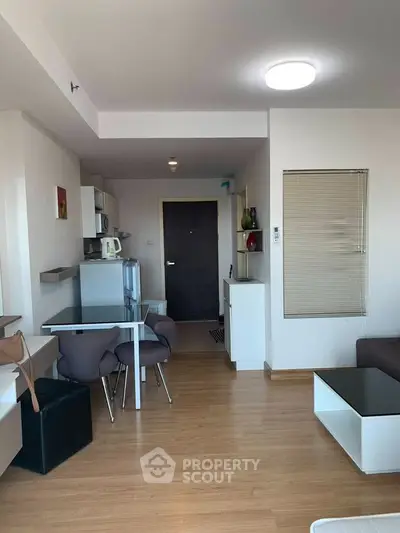 Modern living room with dining area and kitchenette in open layout apartment.