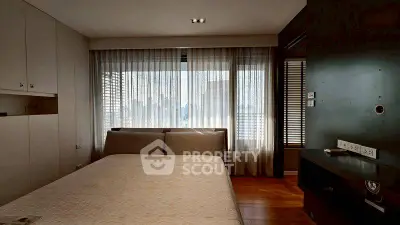 Modern bedroom with large window and elegant decor in urban apartment.