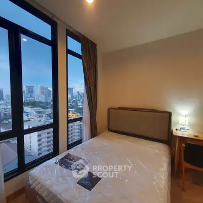 Cozy bedroom with city view and natural light, perfect for urban living.