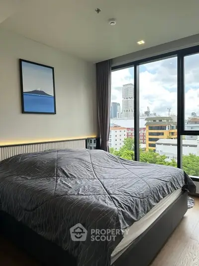 Modern bedroom with large windows offering stunning city view, featuring elegant decor and cozy ambiance.