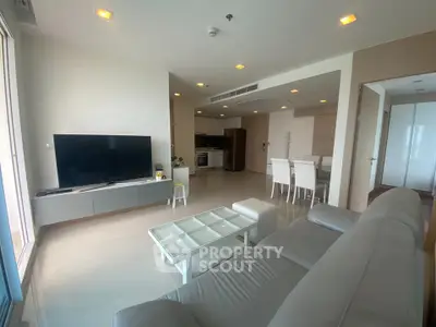 Spacious modern living room with open kitchen and sleek furnishings in a contemporary apartment.