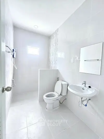 Bright and modern bathroom with sleek white tiles and minimalist fixtures.