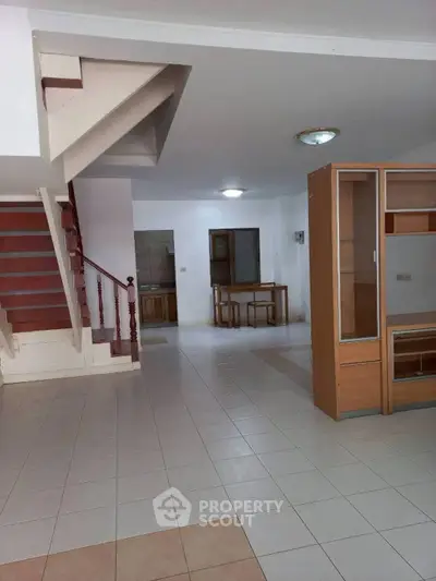 Spacious open-plan living area with staircase and modern cabinetry.