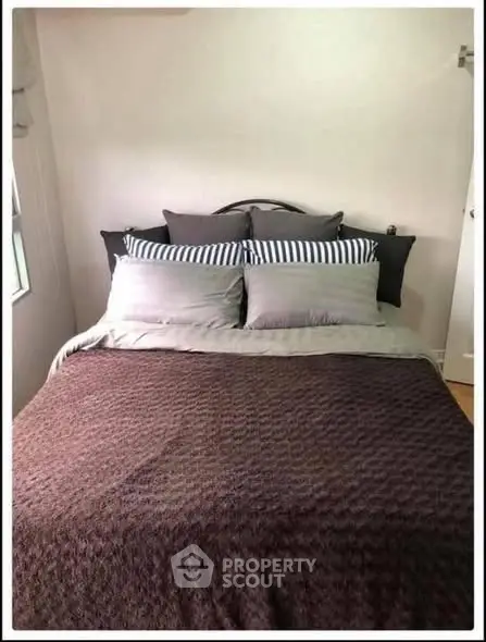 Cozy bedroom with stylish bedding and natural light, perfect for relaxation.