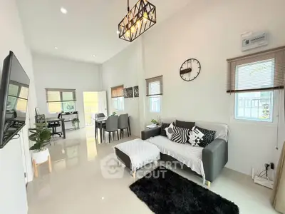 Modern living room with stylish decor and open dining area, featuring sleek furniture and natural light.