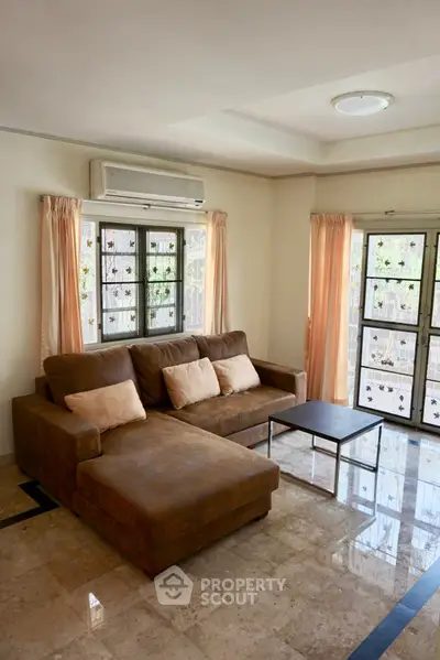 Spacious living room with modern sofa and natural light, perfect for relaxation.