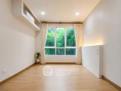 Spacious empty room with large window and wooden flooring, ideal for customization.