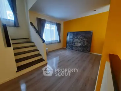 Spacious living room with vibrant yellow accent wall and elegant staircase