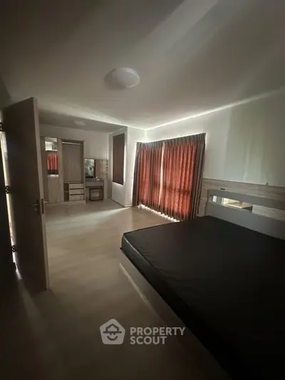 Spacious bedroom with modern furnishings and natural light from large windows.