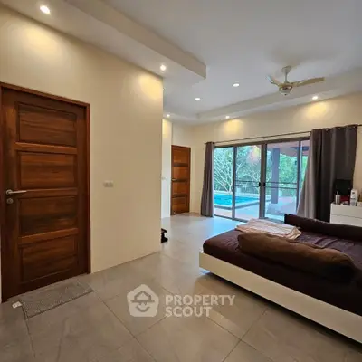 Spacious bedroom with modern design and large windows overlooking greenery.