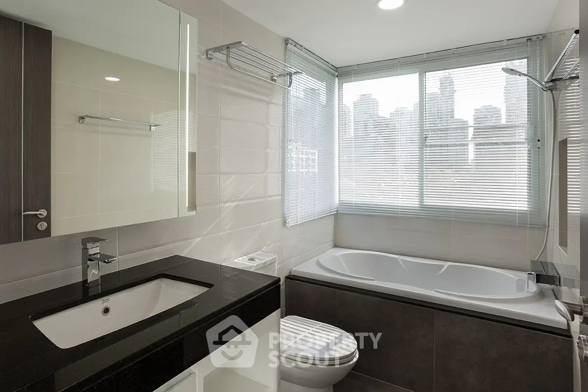 Modern bathroom with city view, featuring sleek fixtures and a luxurious bathtub.