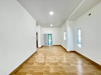 Spacious empty room with wooden flooring and bright natural light
