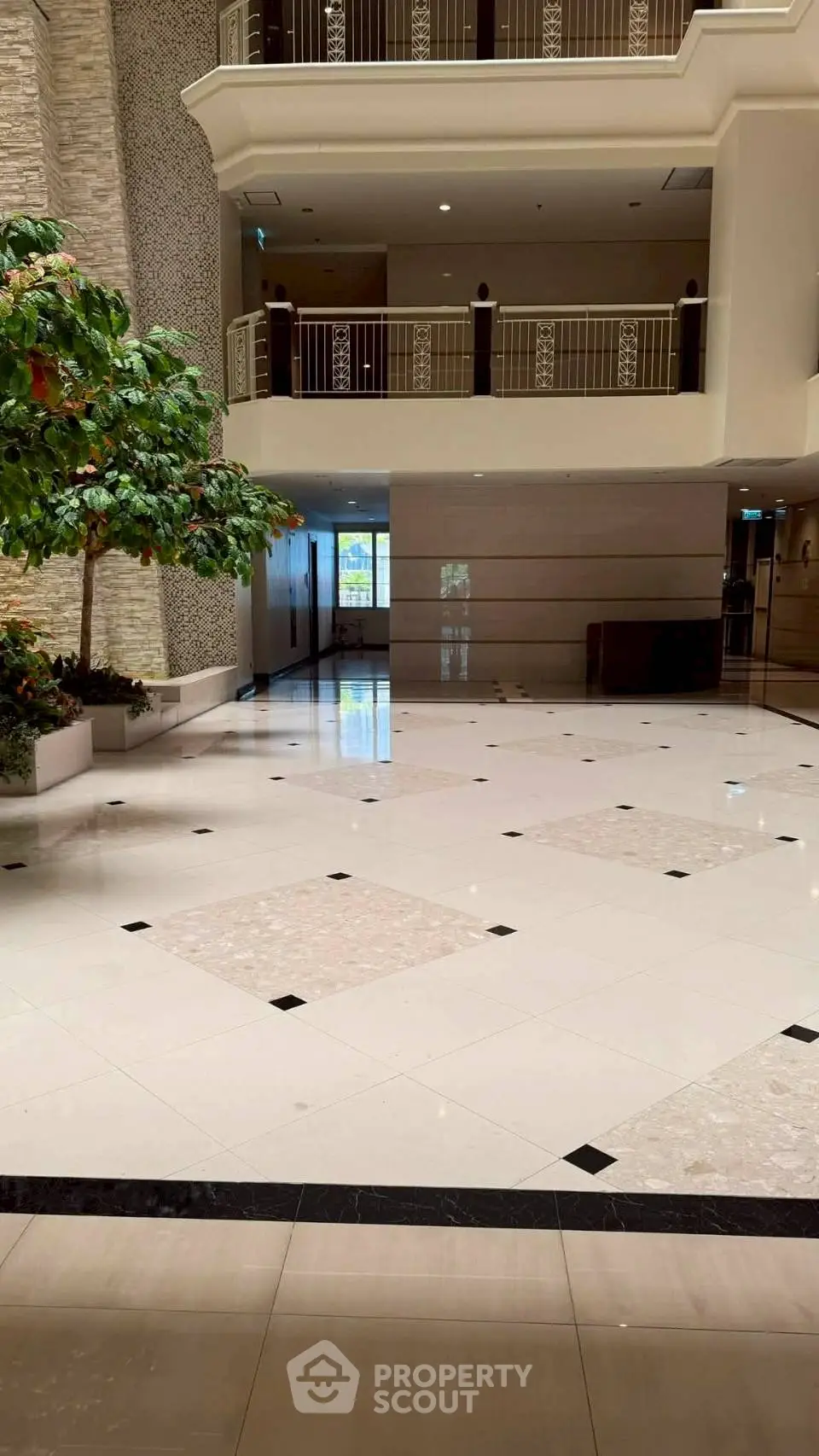 Luxurious building lobby with elegant marble flooring and lush indoor plants.