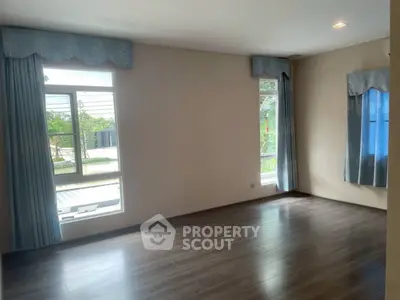 Spacious empty room with large windows and elegant curtains, perfect for customization.