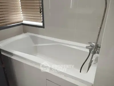 Modern bathroom with sleek bathtub and stylish blinds, perfect for relaxation.