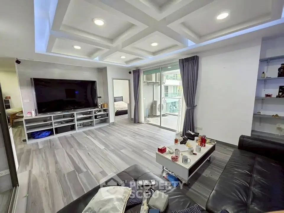 Spacious modern living room with sleek design and large TV, perfect for entertainment.