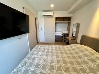Modern bedroom with wall-mounted TV and built-in wardrobe in a stylish apartment.