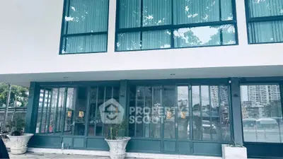 Modern building exterior with large glass windows and potted plants, showcasing urban architecture.