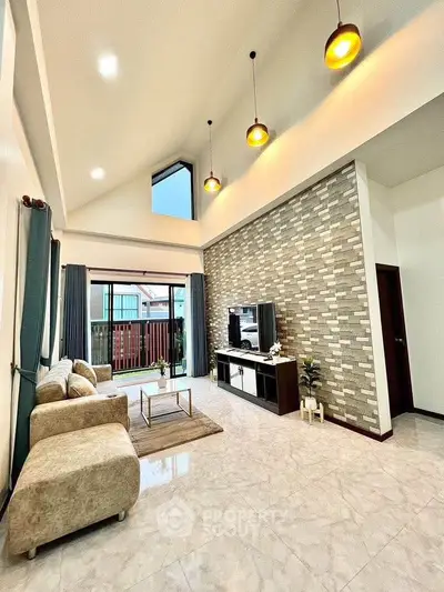 Spacious living room with high ceiling and modern decor, featuring a large window and stylish lighting.