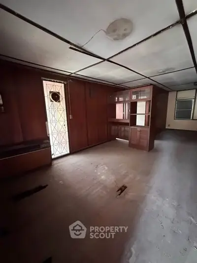 Spacious interior with wooden paneling and built-in shelving, ideal for renovation.