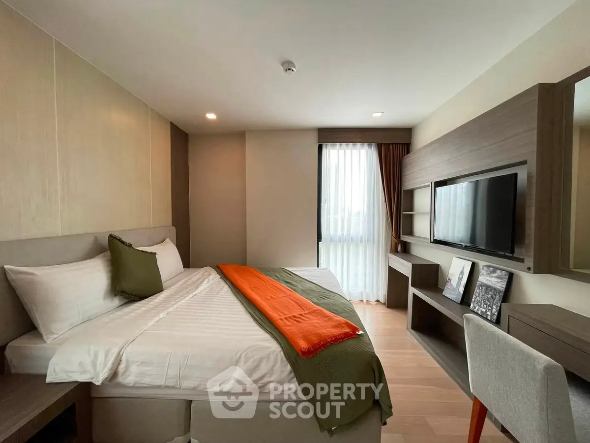 Modern bedroom with stylish decor, featuring a cozy bed, wall-mounted TV, and elegant furnishings.