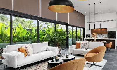 Luxurious modern living room with large windows and lush garden view, featuring stylish furniture and open kitchen layout.