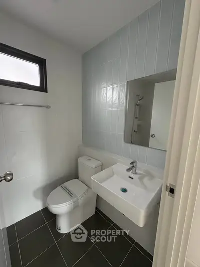 Modern bathroom with sleek fixtures and minimalist design, featuring a compact layout and contemporary tiles.