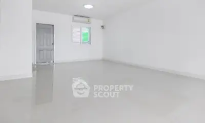 Spacious empty room with white walls and tiled floor, featuring a door and window.