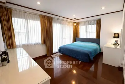 Spacious bedroom with large windows and elegant wooden flooring