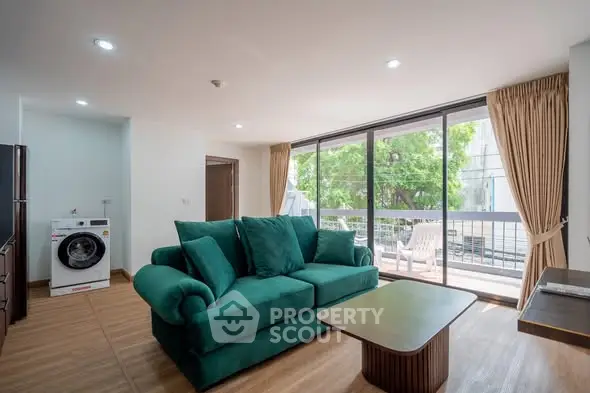 Spacious living room with green sofa and balcony view in modern apartment.