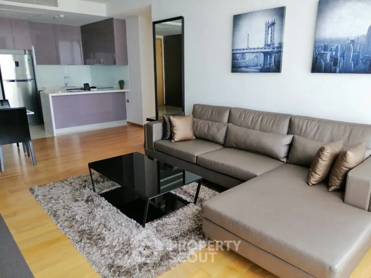 Modern living room with sleek furniture and open kitchen layout in a stylish apartment.