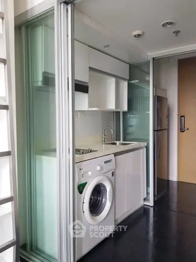 Compact modern kitchen with washing machine and sleek appliances in a stylish apartment.