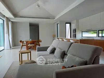 Spacious modern living room with open kitchen and dining area, featuring sleek furniture and natural light.
