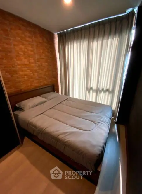 Cozy bedroom with brick accent wall and large window with curtains