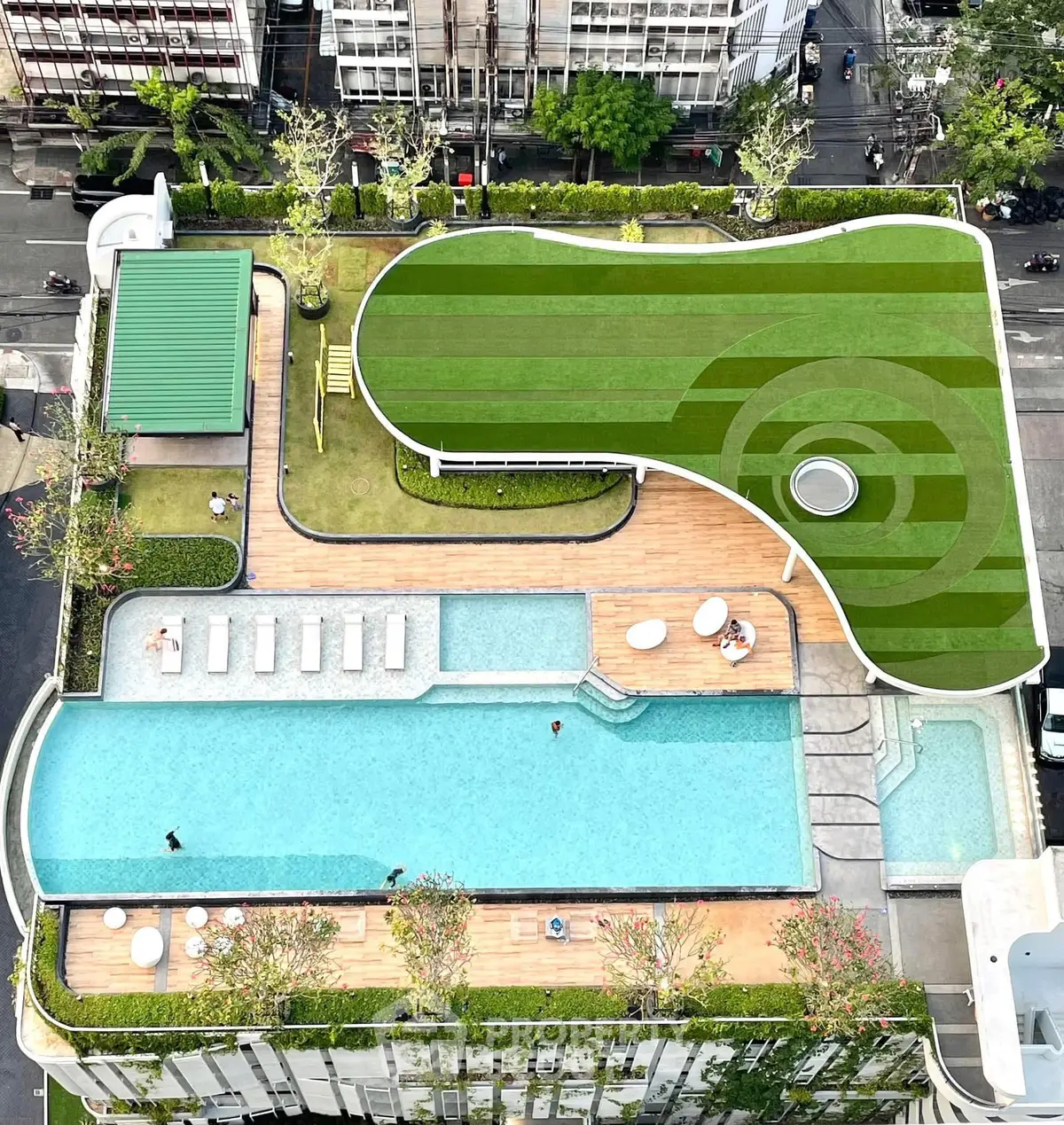 Stunning rooftop pool with lush green terrace and city views, perfect for relaxation and leisure.