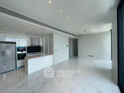 Spacious modern kitchen with sleek white cabinetry and marble flooring in luxury apartment.