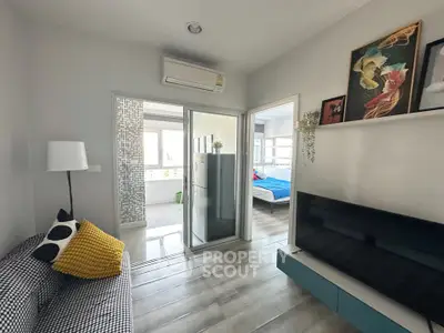 Modern living room with stylish decor and open view to bedroom, featuring sleek furniture and vibrant accents.