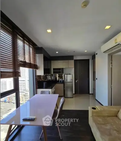 Modern apartment interior with open kitchen and city view, featuring sleek furniture and natural light.
