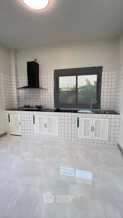Modern kitchen with sleek black countertops and gas stove, featuring a large window for natural light.