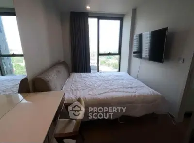 Modern bedroom with large window and wall-mounted TV in a stylish apartment.