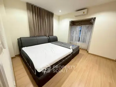 Spacious bedroom with modern furnishings and natural light, featuring a comfortable bed and elegant curtains.