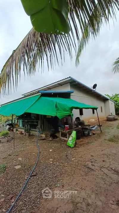 Charming rural house with green awning and lush surroundings, perfect for nature lovers seeking tranquility.