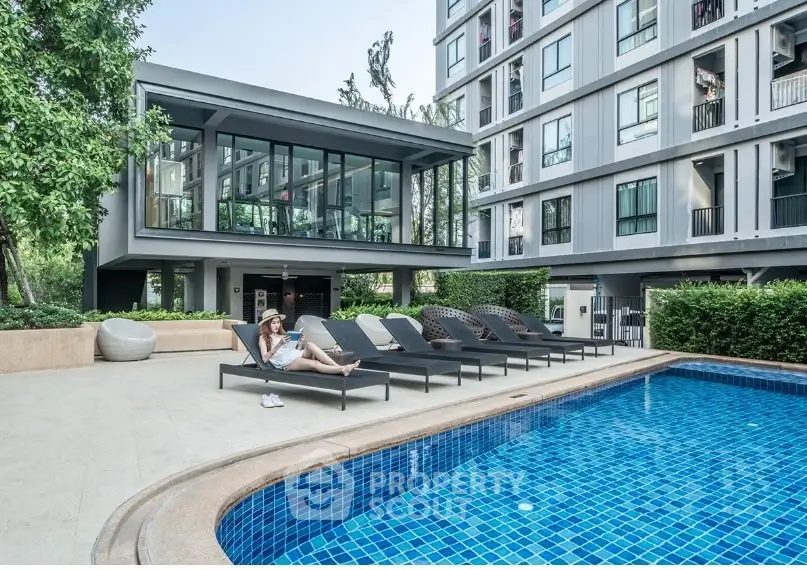 Modern apartment complex with poolside relaxation area and lush greenery.