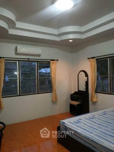 Spacious bedroom with large windows and modern ceiling design, featuring air conditioning and elegant curtains.