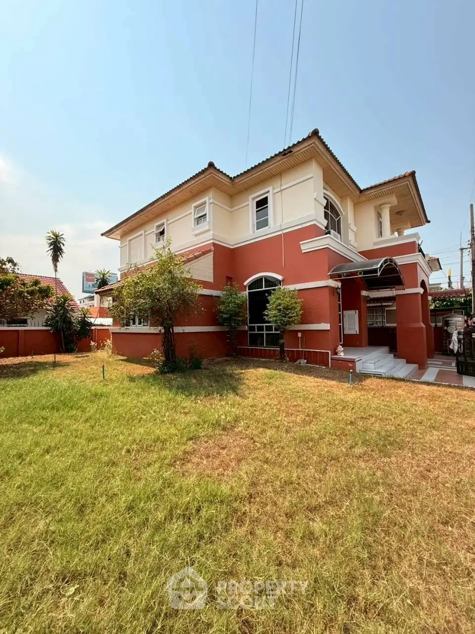 Charming two-story red brick house with lush green lawn and spacious outdoor area.