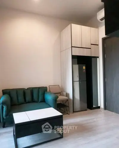 Modern living room with stylish furniture and compact kitchen area in a cozy apartment.