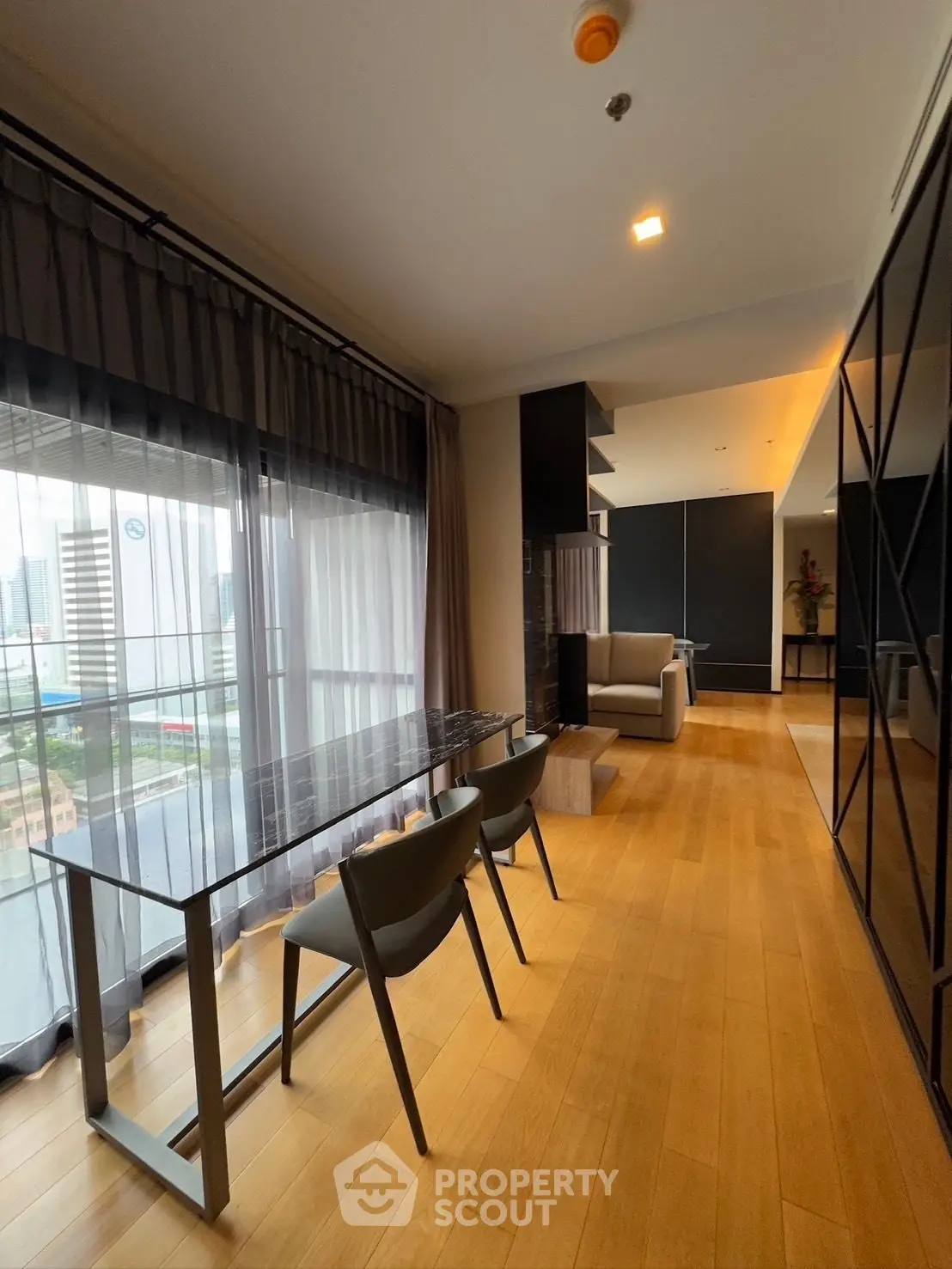 Modern living room with city view, elegant dining area, and floor-to-ceiling windows.