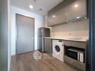 Modern kitchen with sleek appliances and wooden flooring in a compact layout.